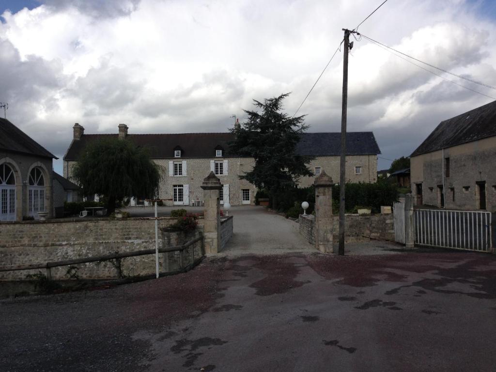 an old house with a stone fence and a street at Domaine Saint-Hilaire in Saint-Hilaire-Petitville