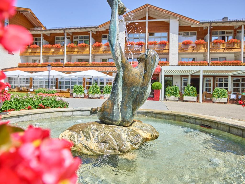 a statue of a woman sitting on a rock in a fountain at Parkhotel Bad Griesbach in Bad Griesbach