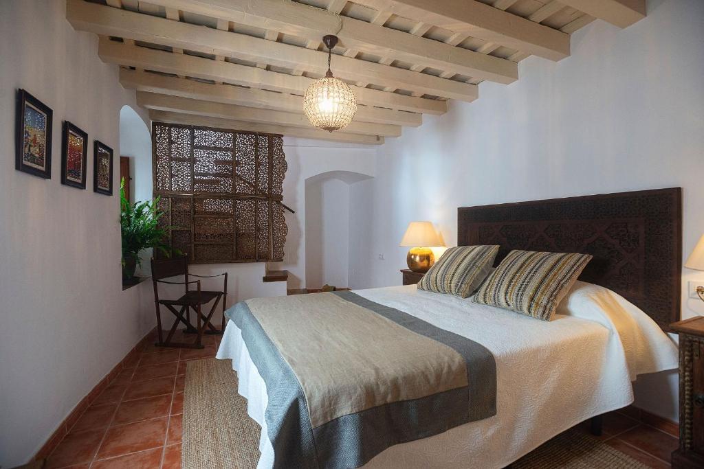 a bedroom with a bed and a chandelier at Las Palmeras del Califa in Vejer de la Frontera