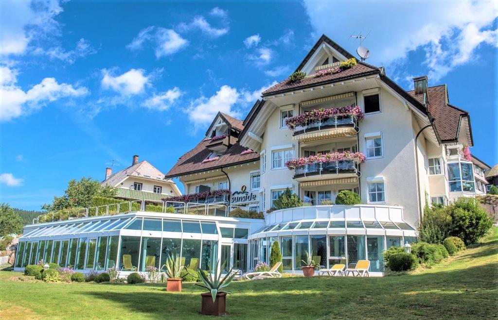 un gran edificio blanco con salón acristalado en Villa Sunside Appartements und Ferienwohnungen Schluchsee, en Schluchsee