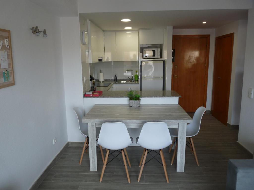 a kitchen with a wooden table and four white chairs at Apartamento Salou in Salou