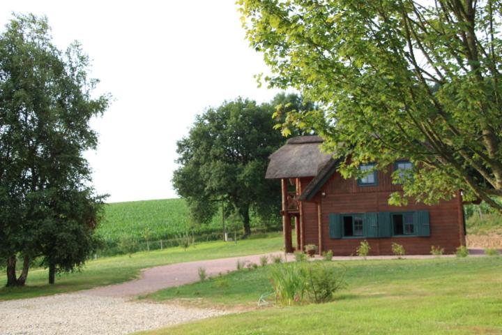 una pequeña casa de madera en un campo con una carretera en Chaumière d'Albâtre -Gîte-Détente nature et bien être, en Ourville-en-Caux