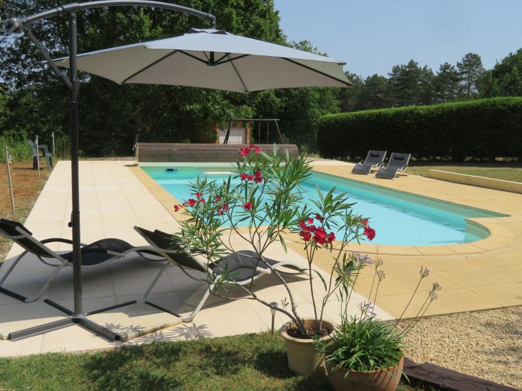Una sombrilla y sillas junto a una piscina. en Le Coze, en Saint-Martial-de-Nabirat