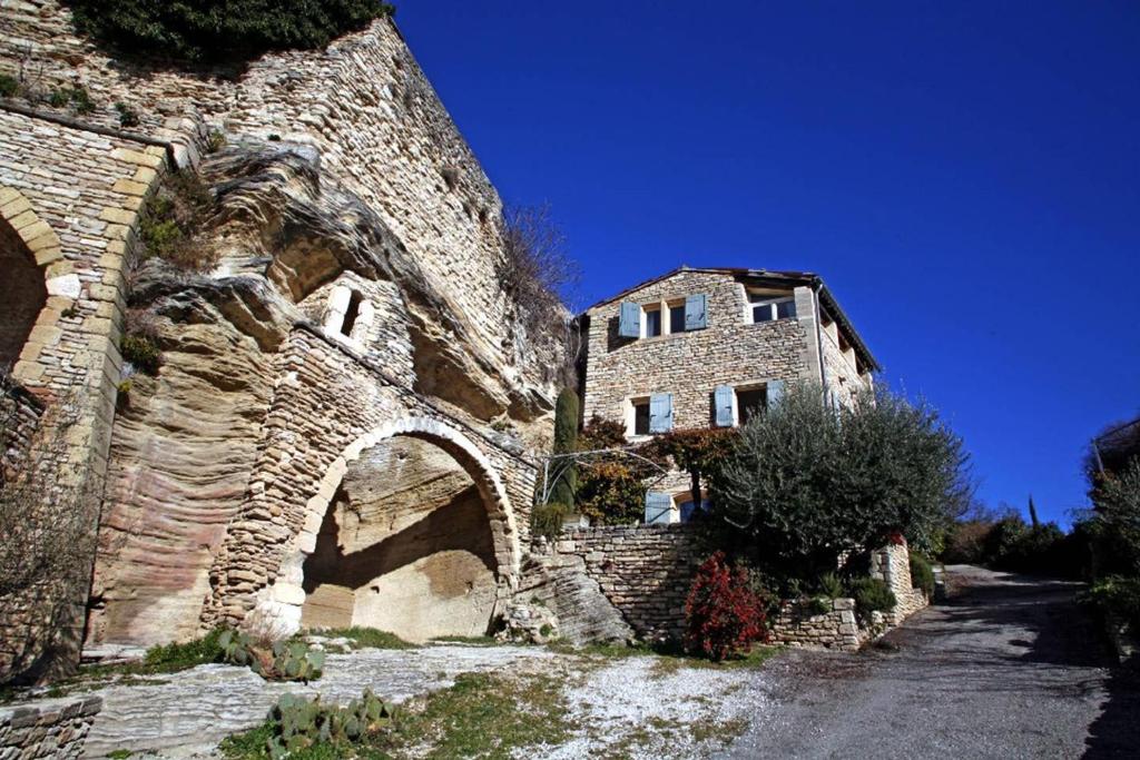 an old stone building with an archway next to a road at Le Bonheur in Gordes