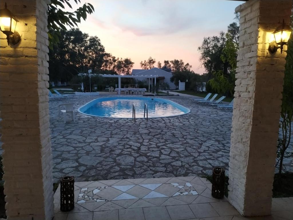 una piscina en un patio con un patio de piedra en Alykes Family Resort en Lefkímmi