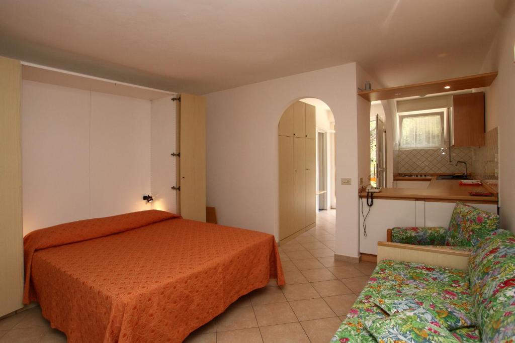 a bedroom with an orange bed and a kitchen at Residence Casa Di Caccia in Marina di Bibbona