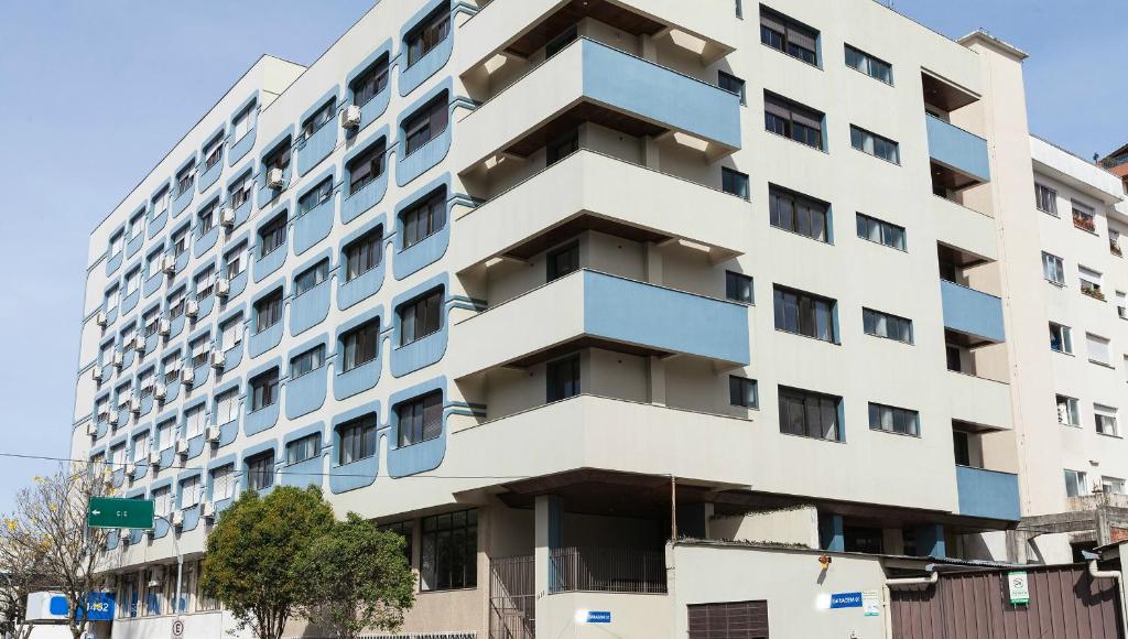 a tall white building with blue windows at Hotel Letto Caxias in Caxias do Sul