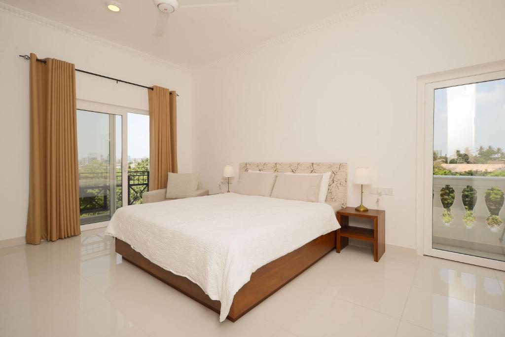 a white bedroom with a bed and a large window at De Saram Residencies in Colombo