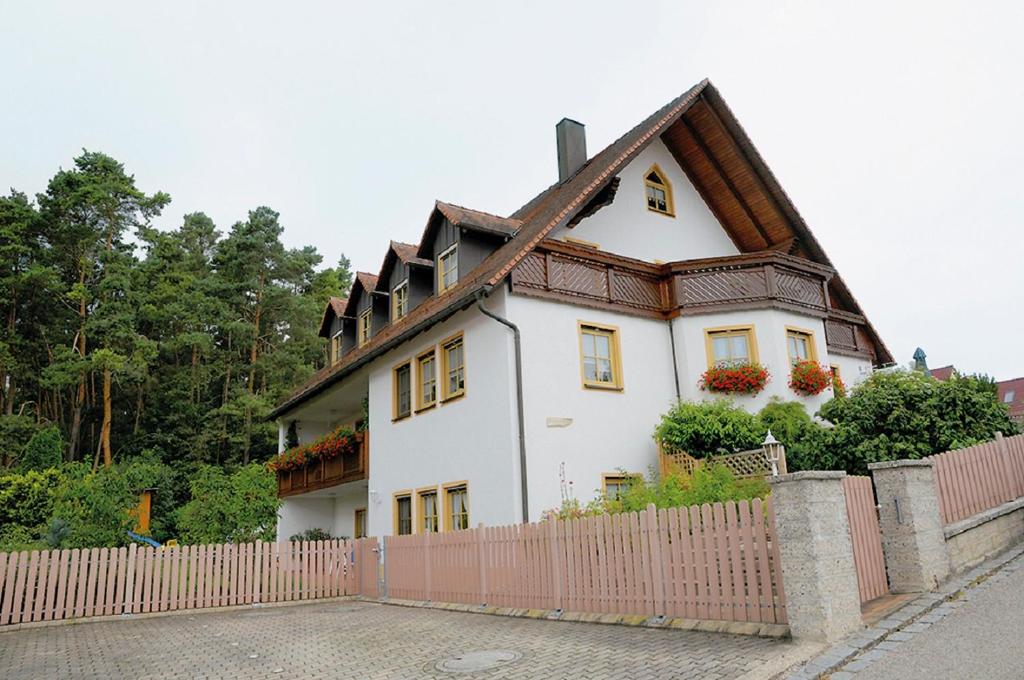 a white house with a fence in front of it at Ferienwohnungen Lehner in Mitteleschenbach