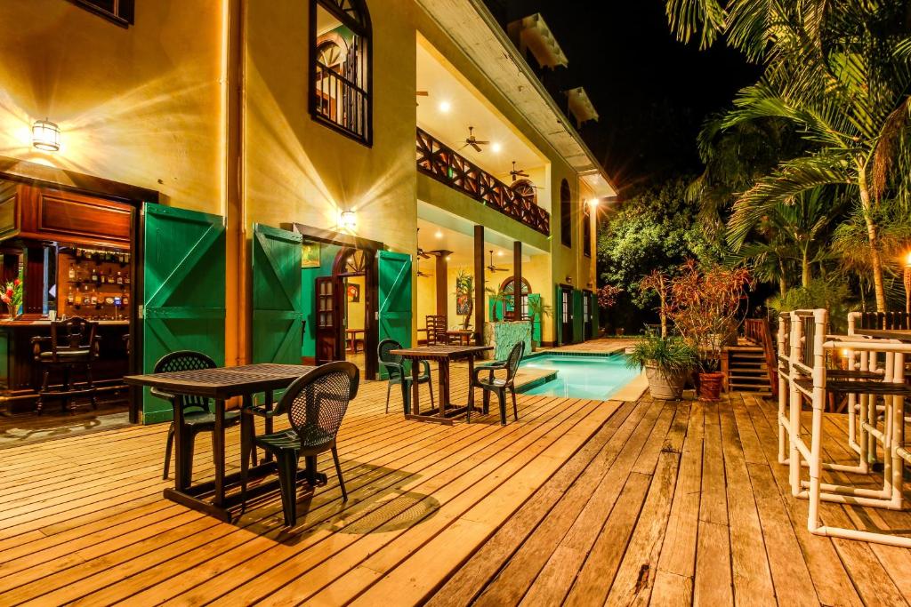 una terrazza in legno con tavoli e sedie accanto alla piscina di Mahogany Hall a San Ignacio