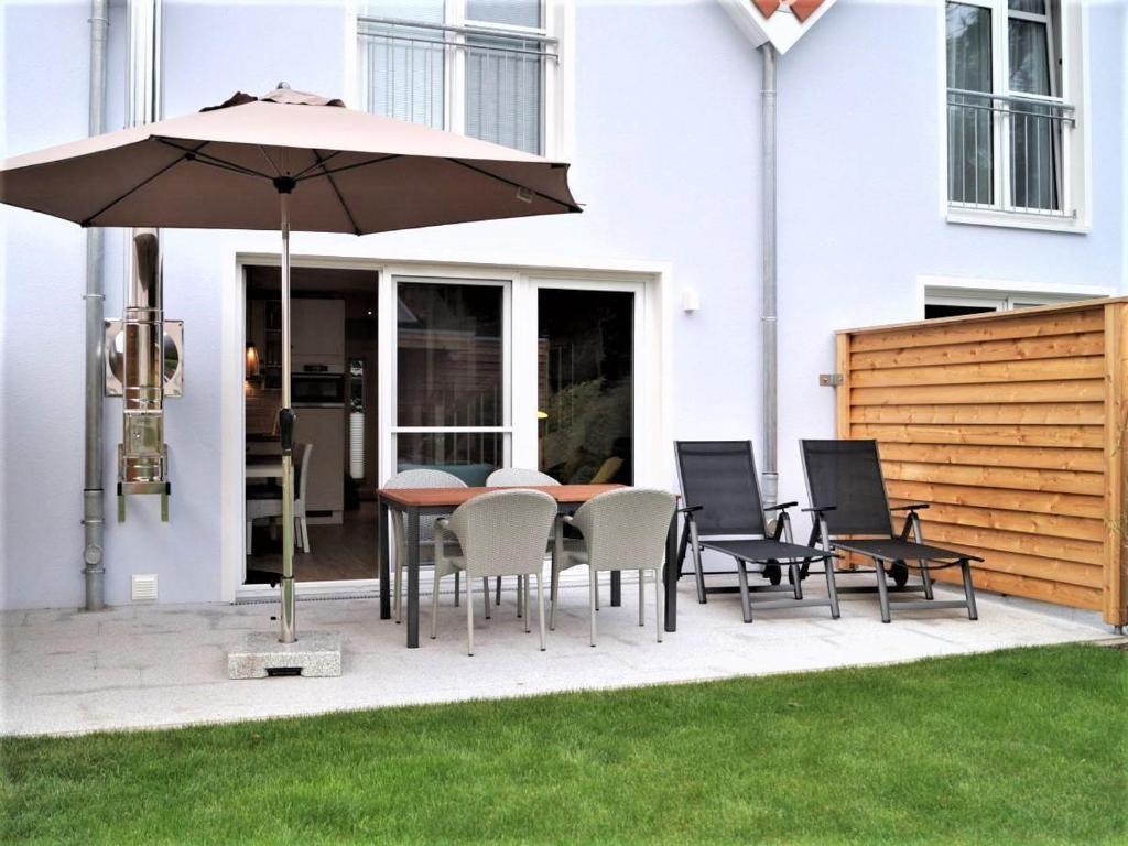 a patio with a table and chairs and an umbrella at Sandkorn-H in Hohwacht