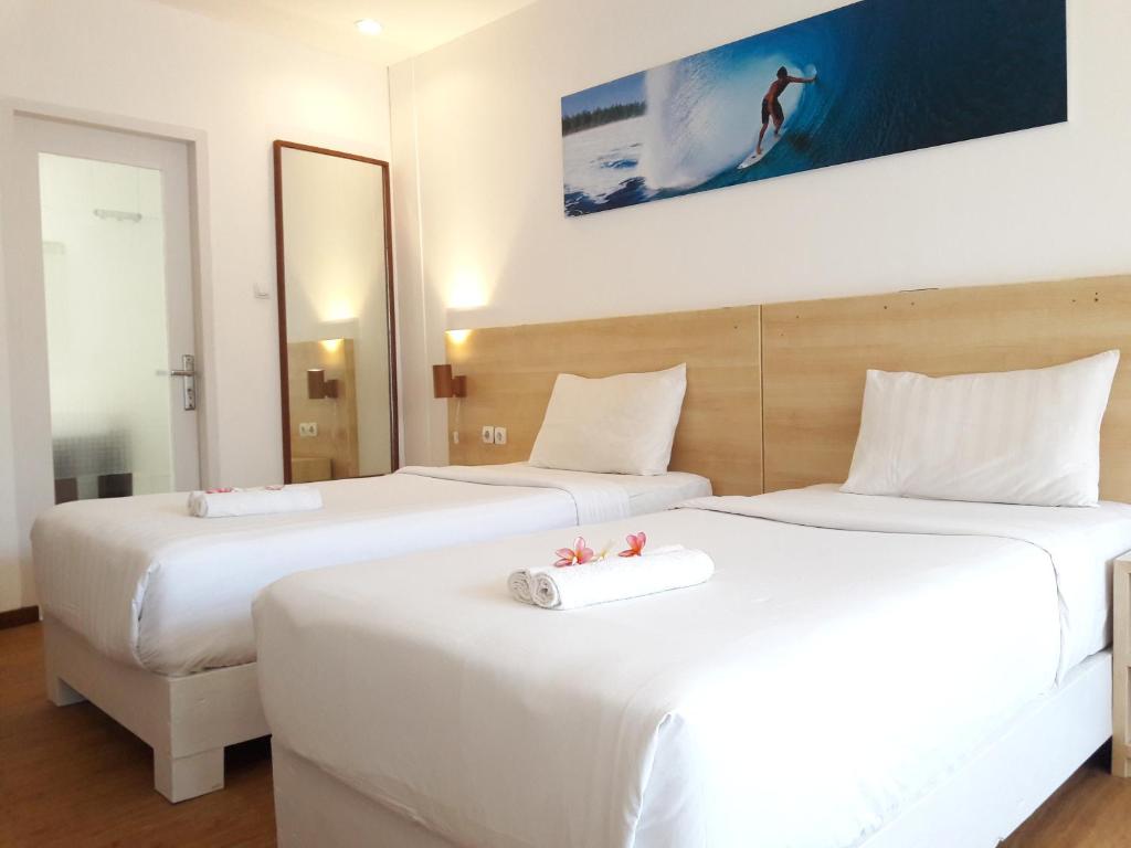 two beds in a hotel room with white sheets at Villa PhyPhy in Gili Trawangan