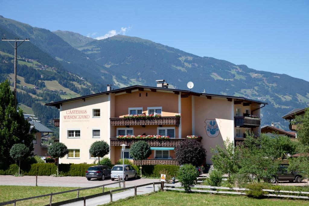 un gran edificio con montañas en el fondo en Gästehaus Wiesengrund & Apart Sporer, en Mayrhofen