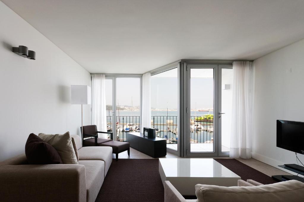 a living room with a couch and a large window at Troia Residence by The Editory - Apartamentos Marina in Troia