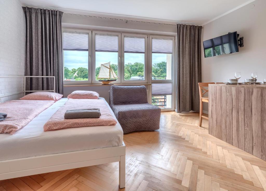 a bedroom with a bed and a chair and windows at Studio Mini Moris - ACCO RENT in Sopot
