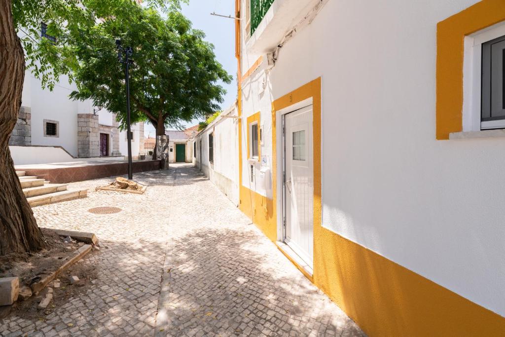 um beco com um edifício amarelo e branco e uma árvore em Santiago Refuge - In the Heart of Alcacer em Alcácer do Sal