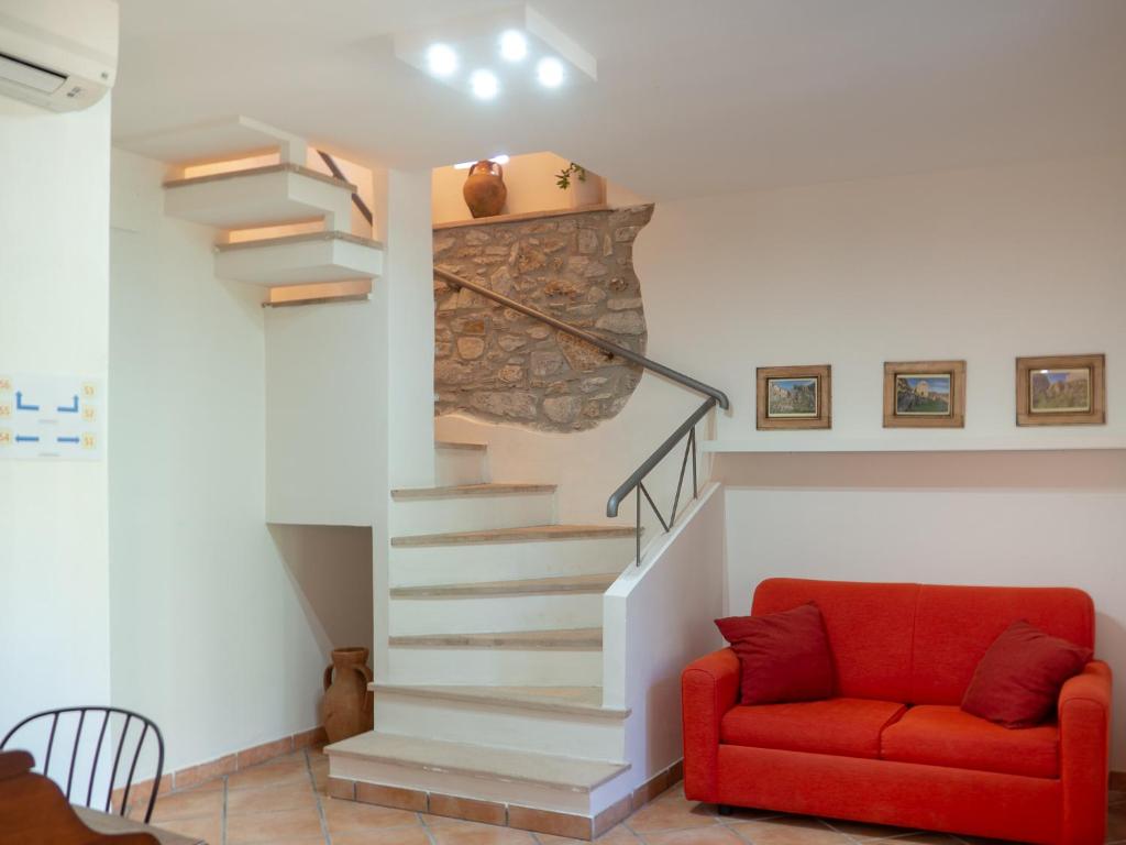 a living room with a staircase and a red couch at Casale Del Borgo in San Severino