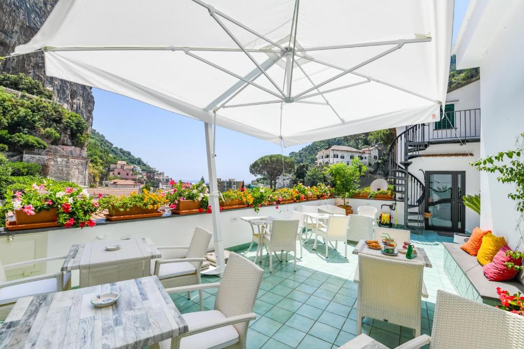 patio ze stołami, krzesłami i parasolem w obiekcie Valle d'Amalfi Suites w Amalfi