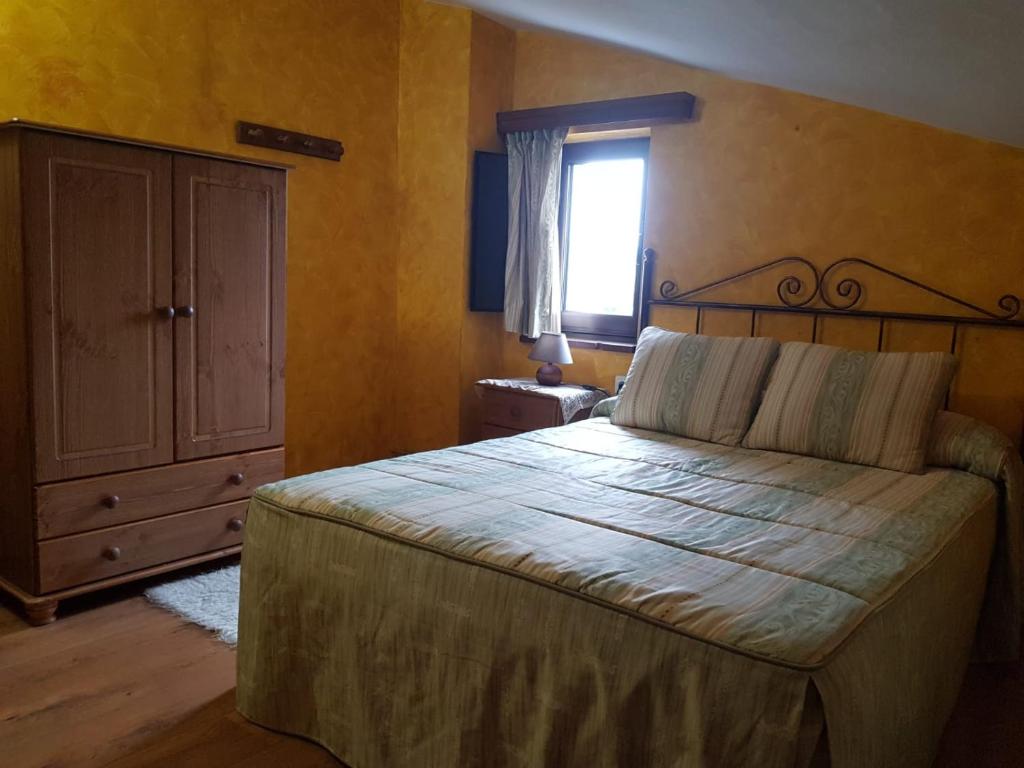 a bedroom with a bed and a dresser and a window at Hostería Carmen in Santillana del Mar