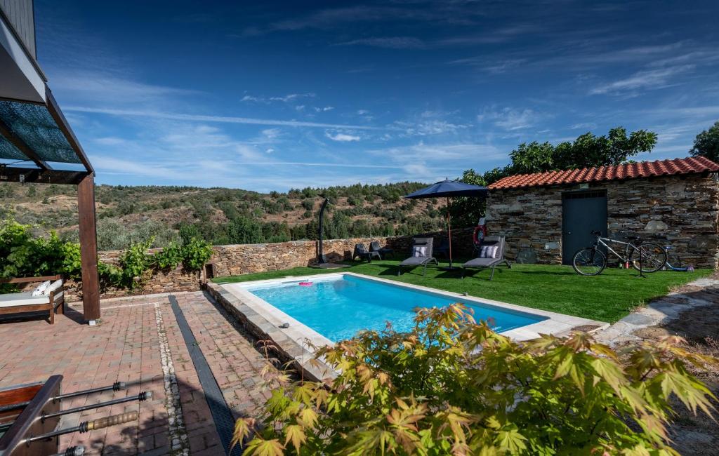 a swimming pool in a yard with a stone house at Casa de Guribanes in Guribanes