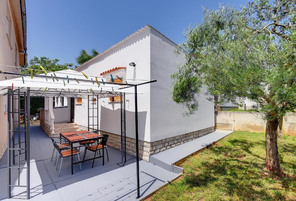 patio ze stołem, krzesłami i drzewem w obiekcie Holiday Home Mihael w Medulinie