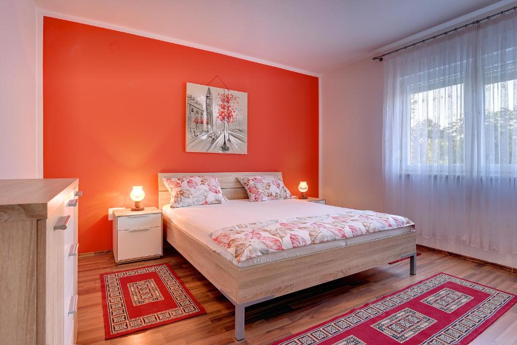 czerwona sypialnia z łóżkiem i oknem w obiekcie Apartment Korpar w Medulinie