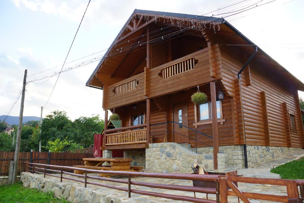 Casa de madera grande con porche y valla en Eco Sadyba Familia en Yaremcha