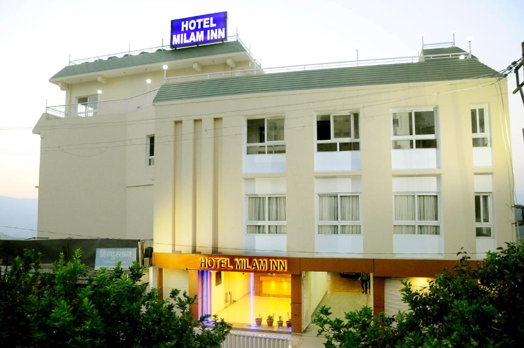 a white building with a sign on top of it at Hotel Milam Inn in Almora