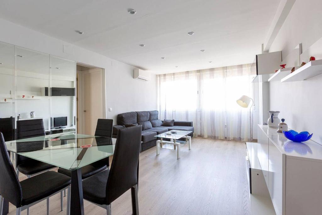 een woonkamer met een glazen tafel en een bank bij Apartamentos La Vaguada Suites in Madrid