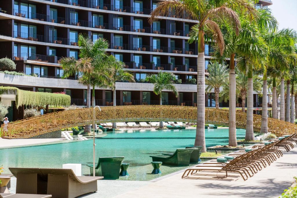 a swimming pool with palm trees and a building at Savoy Palace - The Leading Hotels of the World - Savoy Signature in Funchal