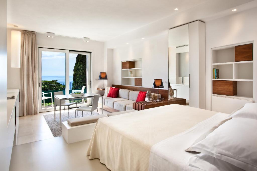 a white bedroom with a bed and a living room at Hotel Villa Belvedere in Taormina