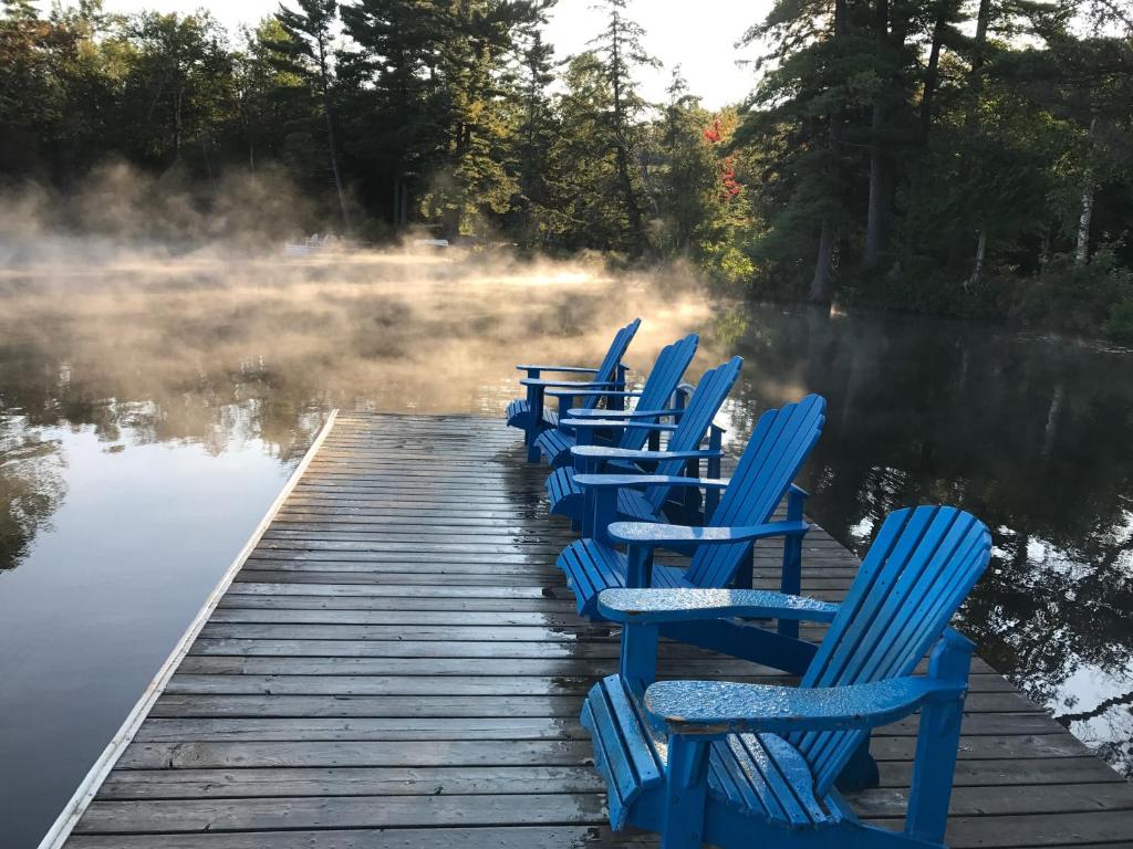 una fila de sillas azules sentadas en un muelle en el agua en Walker Lake Resort en Huntsville