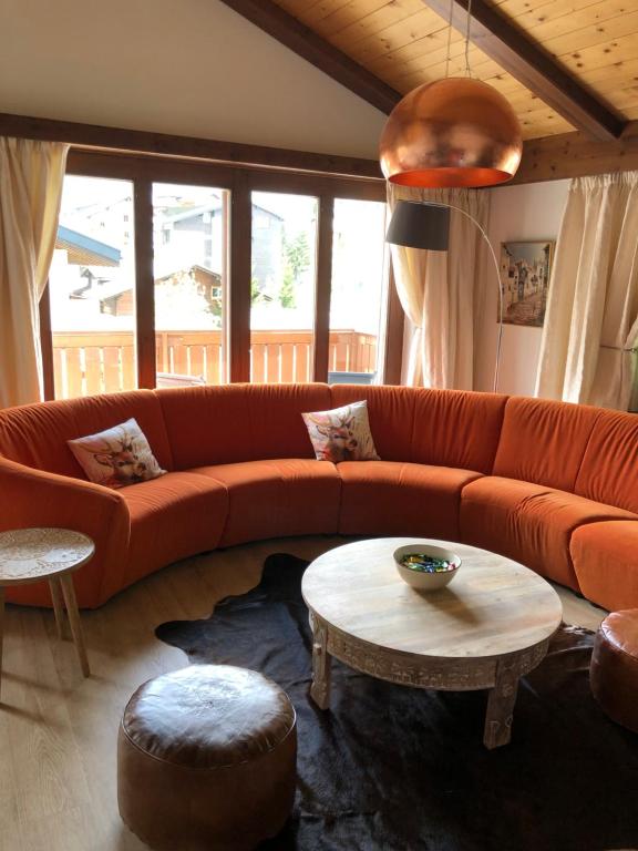 sala de estar con sofá naranja y mesa en Blomatu II Top Floor en Saas-Fee