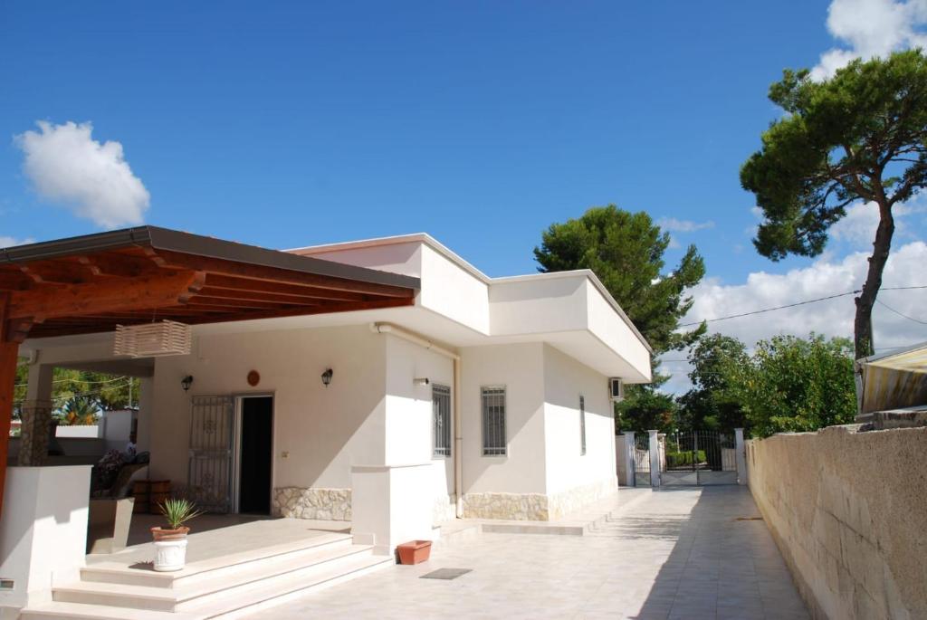 une maison blanche avec un arbre en arrière-plan dans l'établissement Villa Cohiba - 700m dal mare, à Pulsano