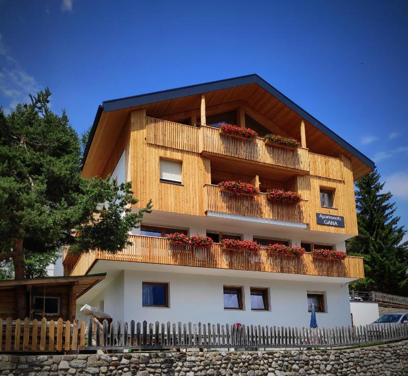 een gebouw met een balkon met rode bloemen erop bij Apartments Gana in La Villa