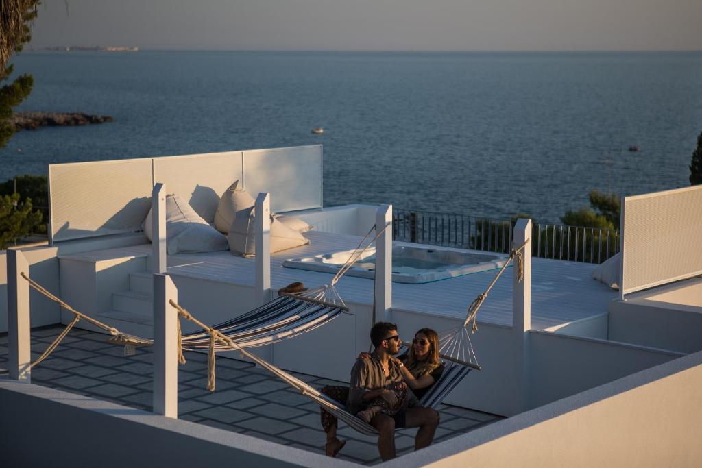 two people sitting in a hammock on a house with the ocean at Senia_rooms_vista in Santa Maria al Bagno