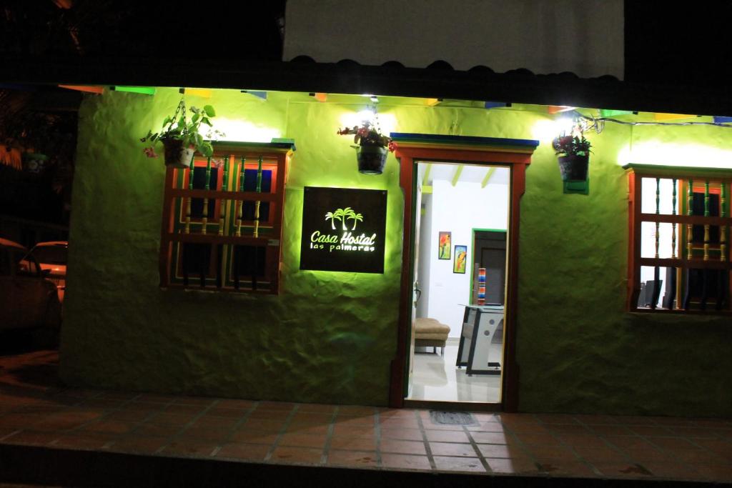 un edificio verde con un cartel que dice buena esposa en casa hostal las palmeras, en Guatapé
