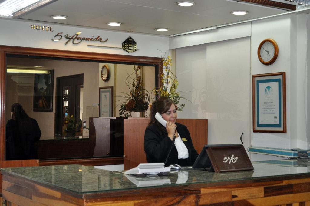 uma mulher sentada numa secretária com um portátil em Hotel 5a Avenida em Monterrey
