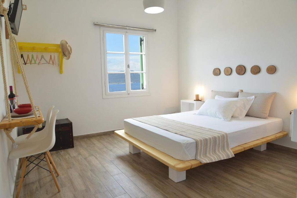 a white bedroom with a bed and a window at Margaritari Studios Milos in Adamas