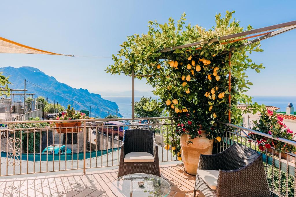 a balcony with chairs and an orange tree and a pool at B&B IL CORTILE in Ravello