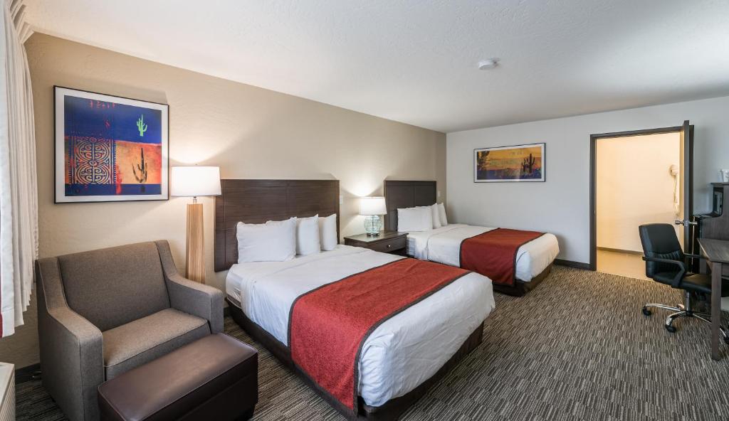 a hotel room with two beds and a chair at Lux Verde Hotel in Cottonwood