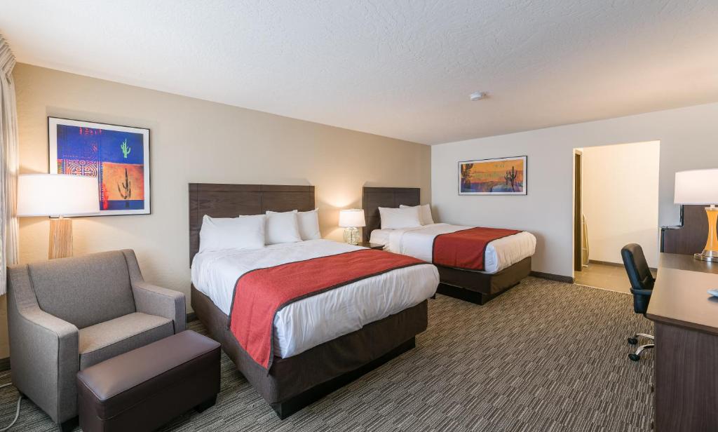 a hotel room with two beds and a chair at Lux Verde Hotel in Cottonwood