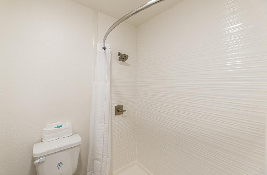 a white bathroom with a shower and a toilet at Lux Verde Hotel in Cottonwood