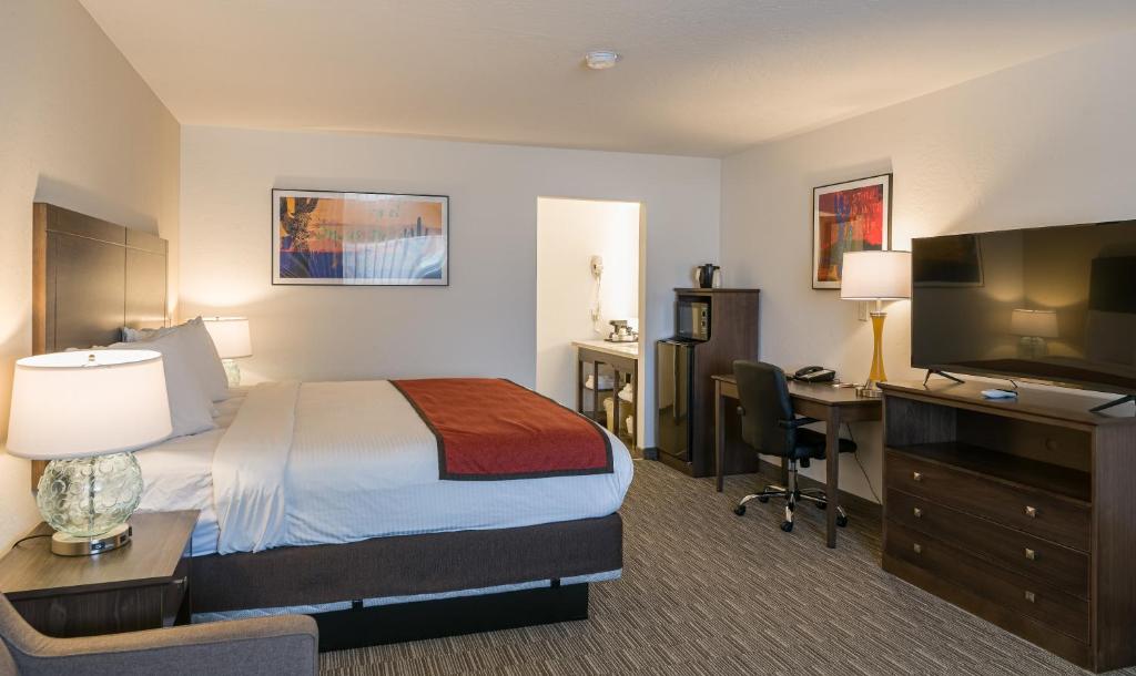 a hotel room with a bed and a desk and a television at Lux Verde Hotel in Cottonwood