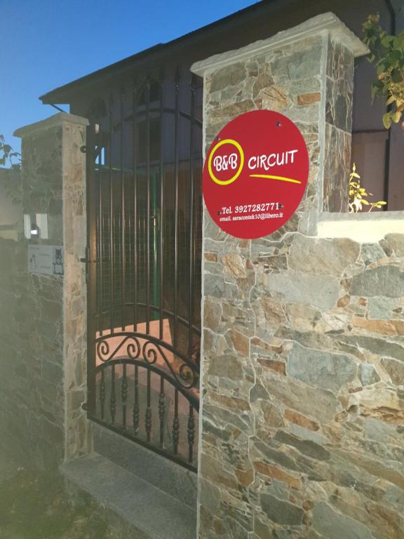 Una puerta en una pared de piedra con un cartel. en B&B Circuit, en Borgo San Lorenzo