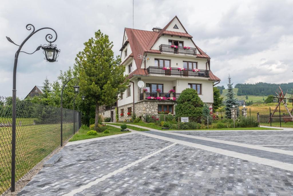 a house on a road in front of a fence at Pokoje Gościnne Sarenka - noclegi w pobliżu Tatr in Czarna Góra