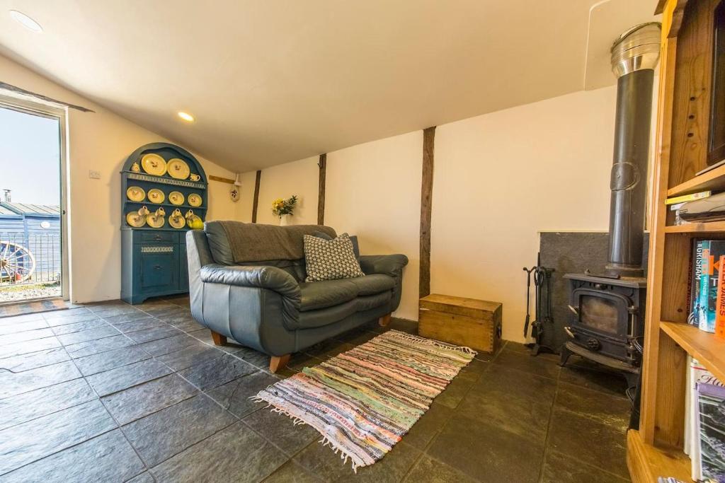 a living room with a couch and a stove at The Buttery at Woodend in Broughton in Furness