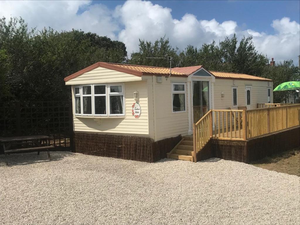 a small white shed with a porch and a bench at Countryside views from a luxury mobile home near Perranporth in Perranporth