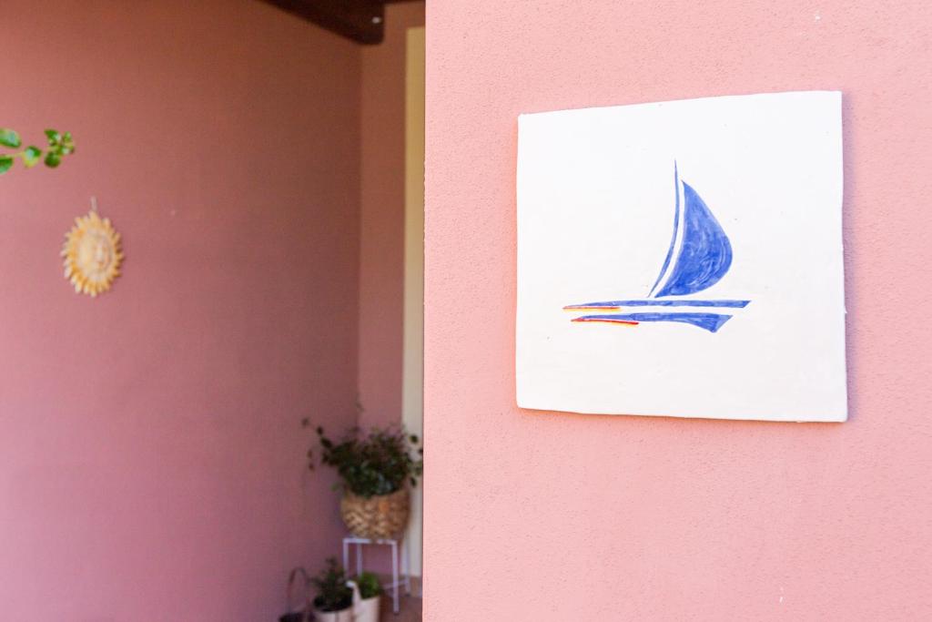 a painting of a sail boat on a pink wall at B&B La Vela Chia in Chia