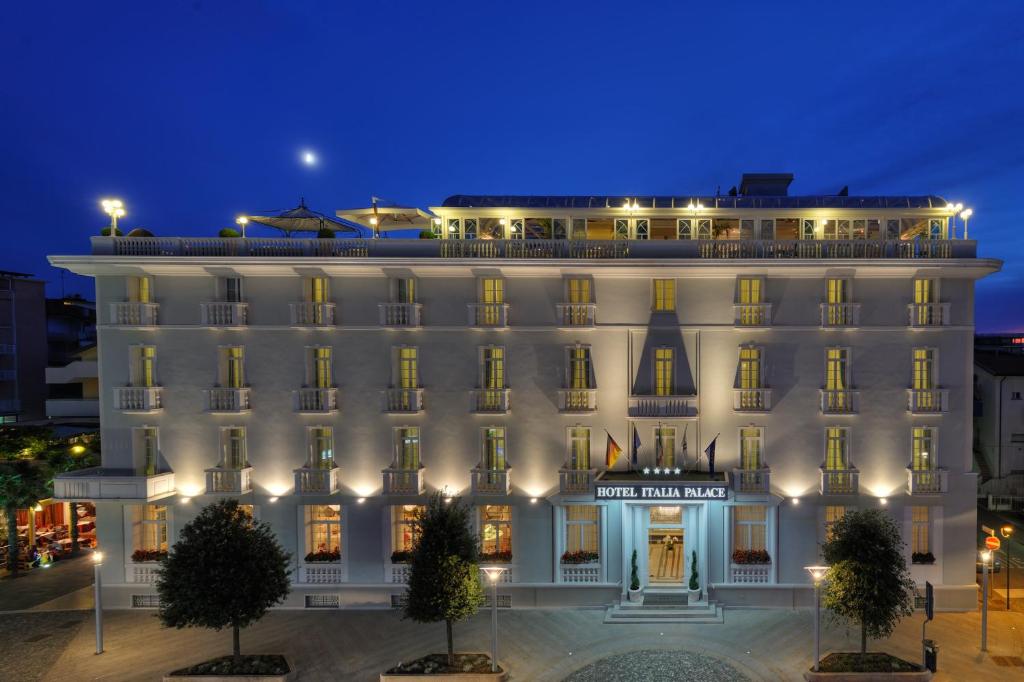 a large white building at night at Hotel Italia Palace in Lignano Sabbiadoro